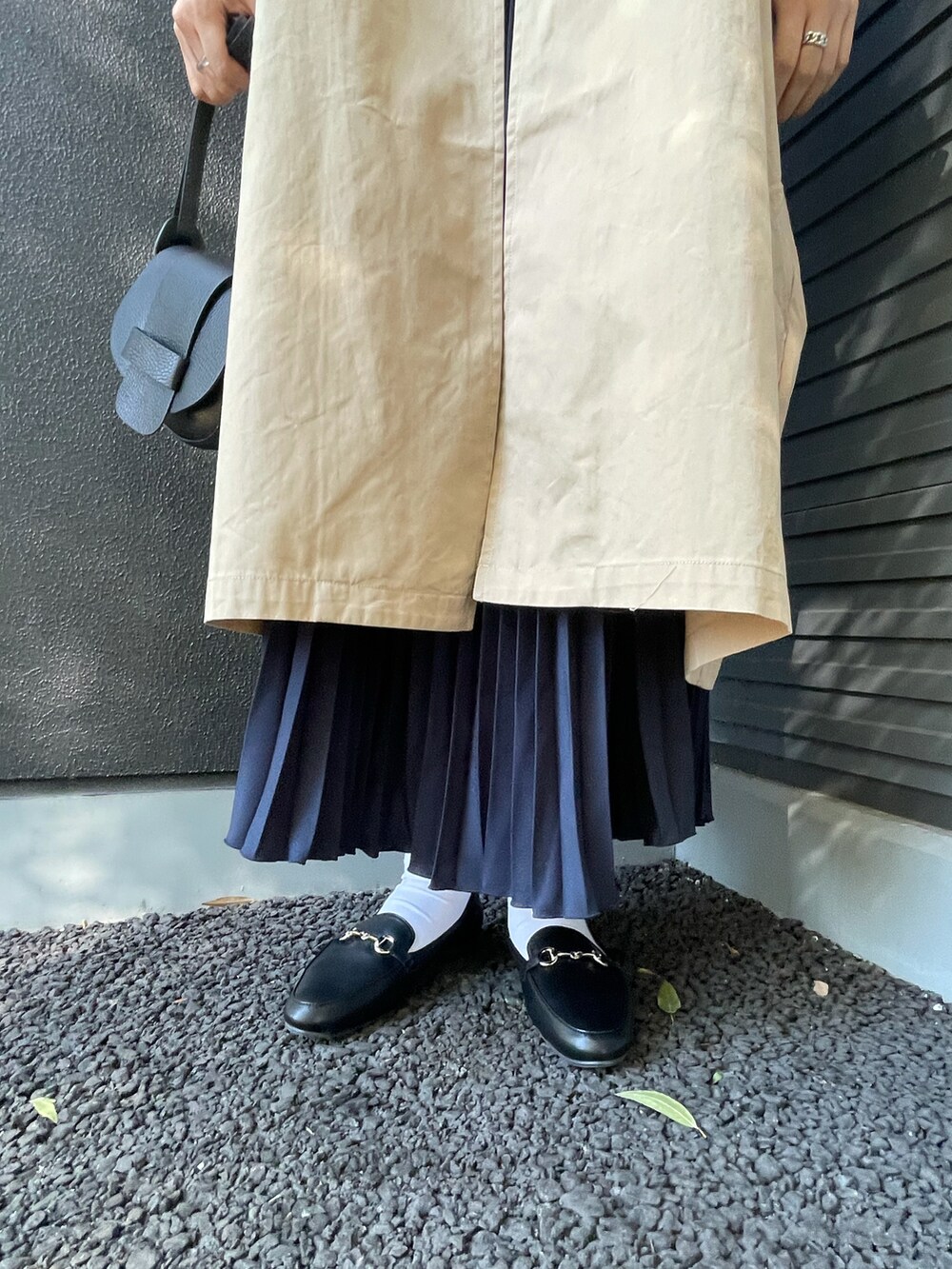 ベージュ系のステンカラーコート、レッド系のTシャツ/カットソー、ブラック系のショルダーバッグを着用したレディースの冬コーディネートの3枚目の写真