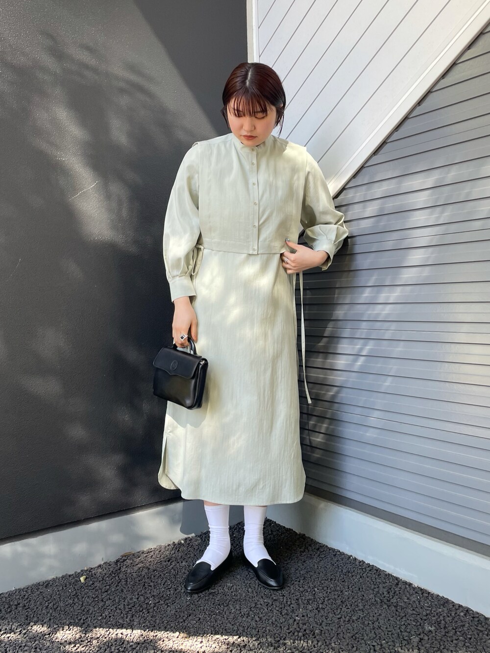 グリーン系のワンピース、ブラック系のバッグ、ブラック系のスリッポンを着用したレディースの冬コーディネートの2枚目の写真