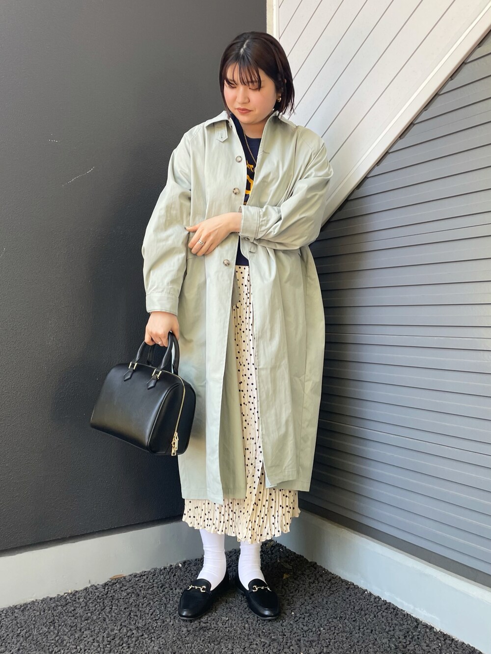 グリーン系のステンカラーコート、ブルー系のスウェット、ホワイト系のスカートを着用したレディースの冬コーディネートの2枚目の写真