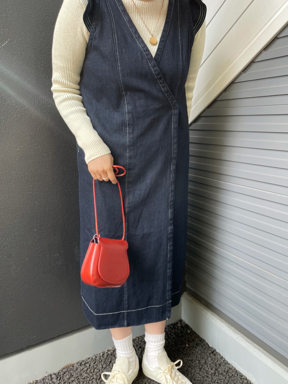 ブルー系のワンピース、ホワイト系のニット/セーター、レッド系のショルダーバッグを着用したレディースの冬コーディネートの3枚目の写真