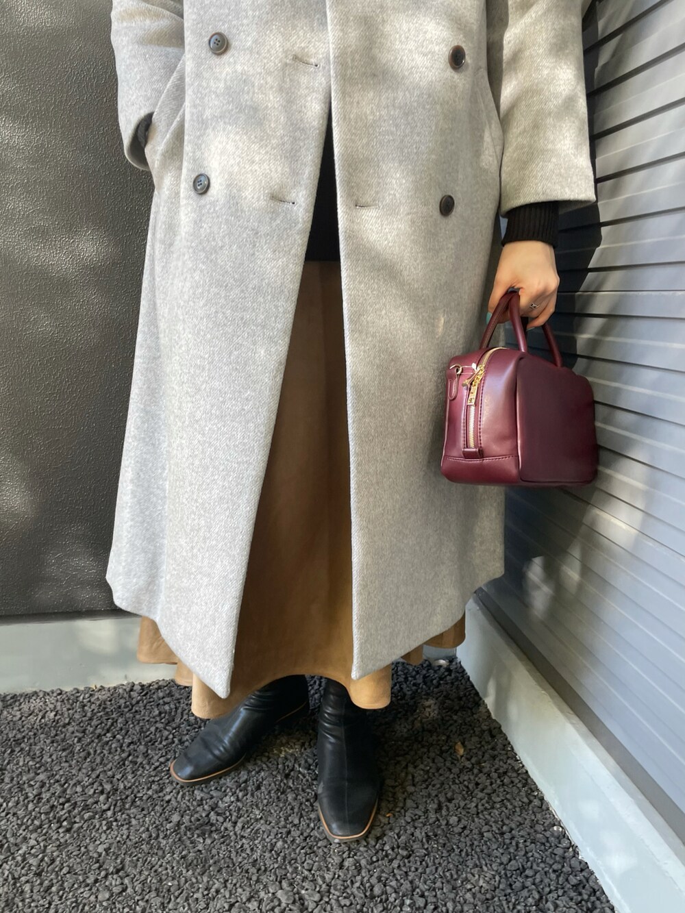 レッド系のボストンバッグ、グレー系のその他アウター、ホワイト系のTシャツ/カットソーを着用したレディースの冬コーディネートの4枚目の写真