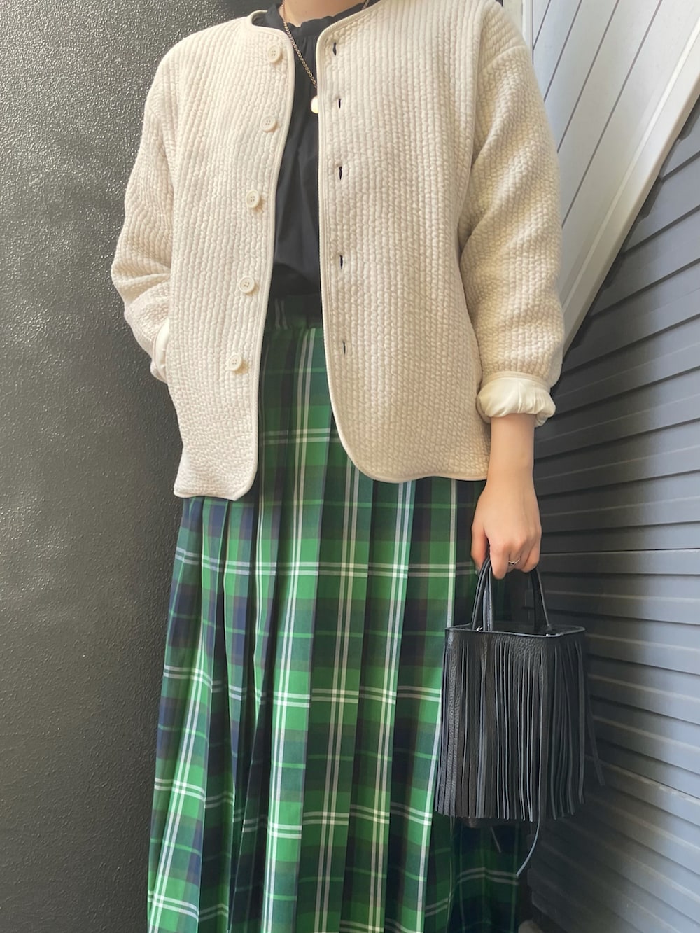 ホワイト系のノーカラージャケット、グリーン系のスカート、ブラック系のハンドバッグを着用したレディースの冬コーディネートの3枚目の写真