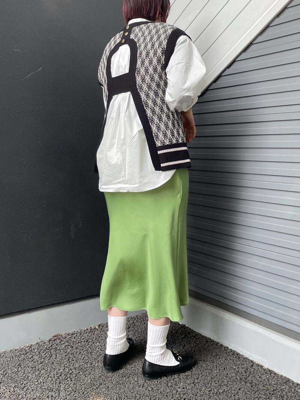 ブラック系のベスト、ホワイト系のシャツ/ブラウス、グリーン系のスカートを着用したレディースの冬コーディネートの2枚目の写真