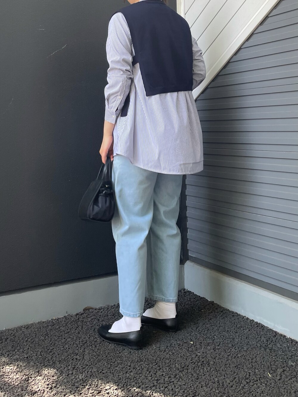 ブラック系のショルダーバッグ、ブラック系のスリッポン、ブルー系のシャツ/ブラウスを着用したレディースの春コーディネートの2枚目の写真