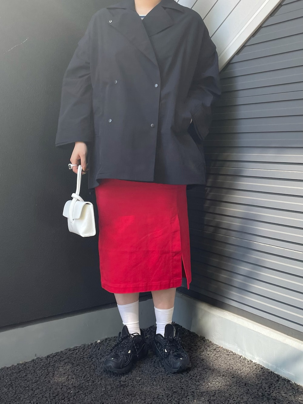 ブルー系のポンチョ、ホワイト系のショルダーバッグ、レッド系のスカートを着用したレディースの冬コーディネートの2枚目の写真