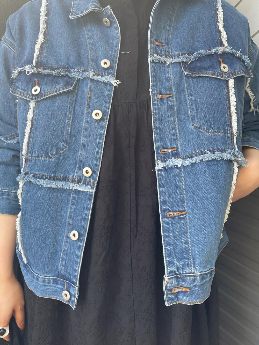 ブルー系のデニムジャケット、ブラック系のワンピース、ブラック系のショルダーバッグを着用したレディースの春コーディネートの3枚目の写真