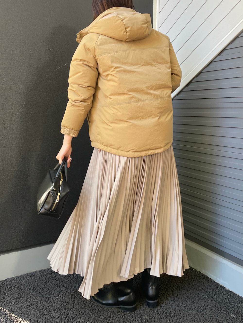 グリーン系のニット/セーター、ベージュ系のダウンジャケット/コート、ブラック系のボストンバッグを着用したレディースの冬コーディネートの2枚目の写真