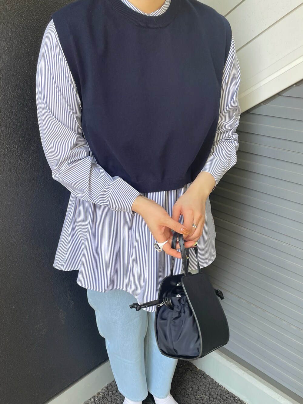 ブラック系のショルダーバッグ、ブラック系のスリッポン、ブルー系のシャツ/ブラウスを着用したレディースの春コーディネートの3枚目の写真