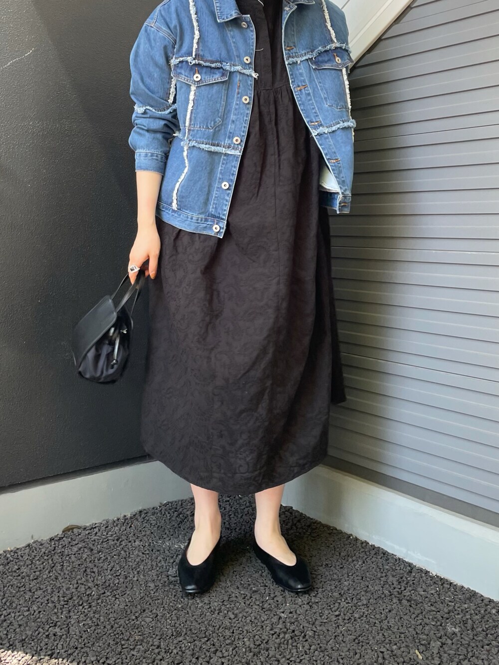 ブルー系のデニムジャケット、ブラック系のワンピース、ブラック系のショルダーバッグを着用したレディースの春コーディネートの2枚目の写真