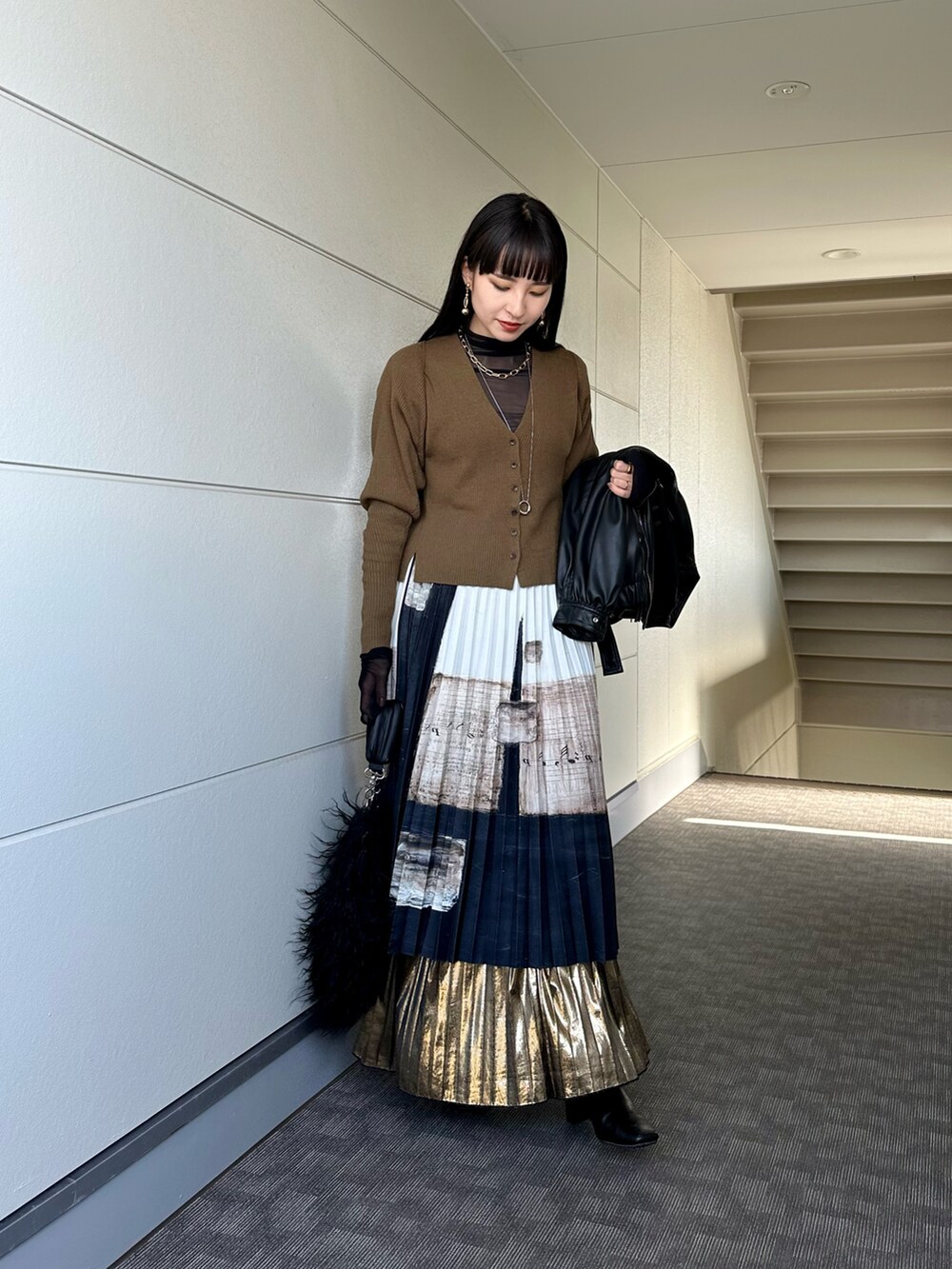 ブラック系のライダースジャケット、ブラック系のトートバッグ、ブラウン系のニット/セーターを着用したレディースの冬コーディネートの5枚目の写真