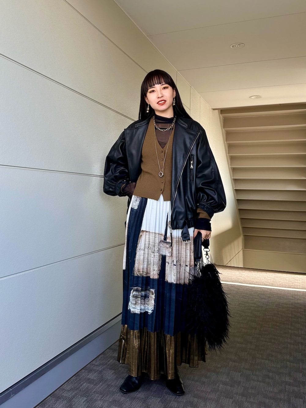 ブラック系のライダースジャケット、ブラック系のトートバッグ、ブラウン系のニット/セーターを着用したレディースの冬コーディネートの4枚目の写真