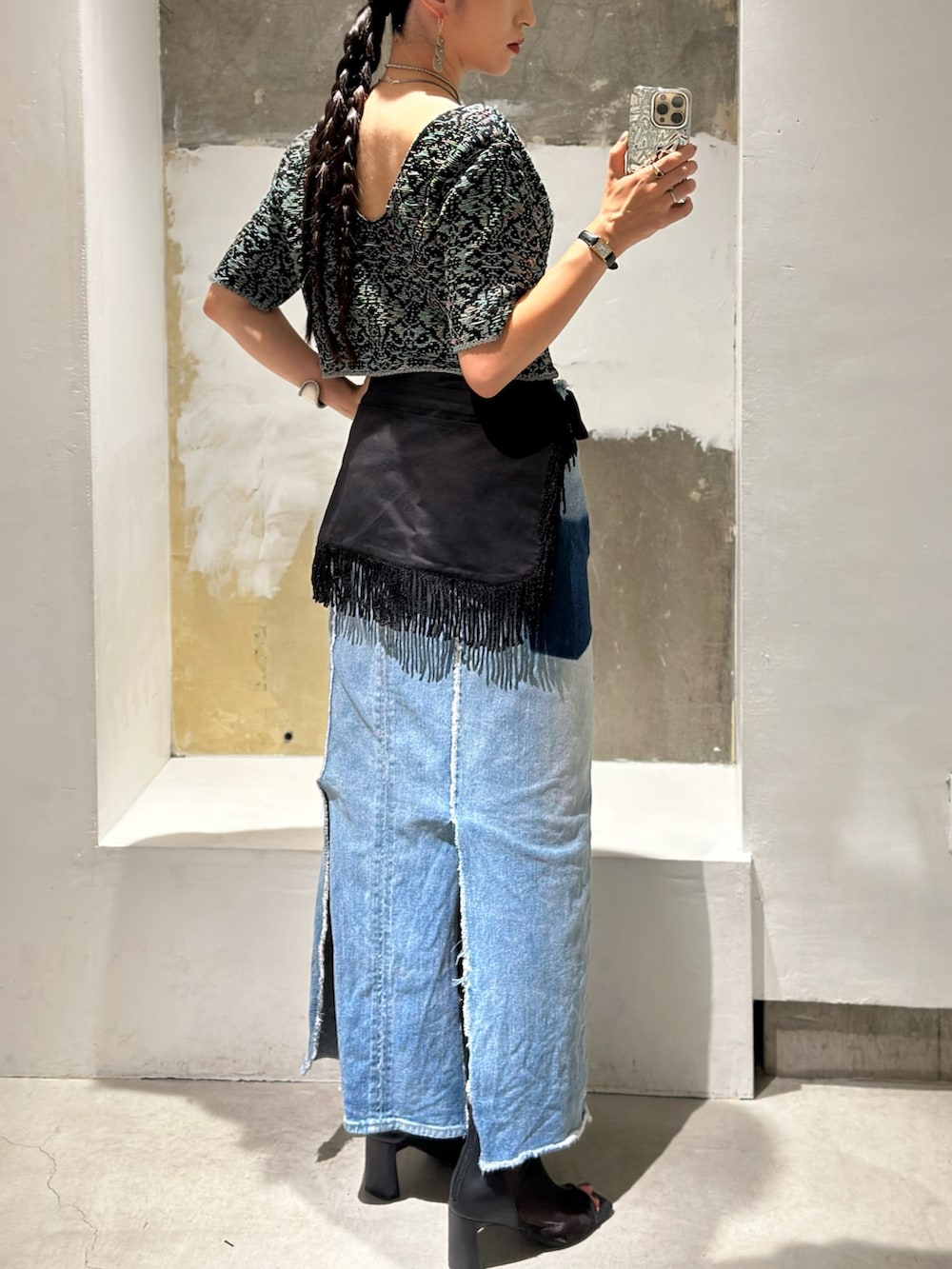 ブルー系のデニムスカート、ブラック系のブーツ、ブラック系のスカートを着用したレディースの秋コーディネートの4枚目の写真