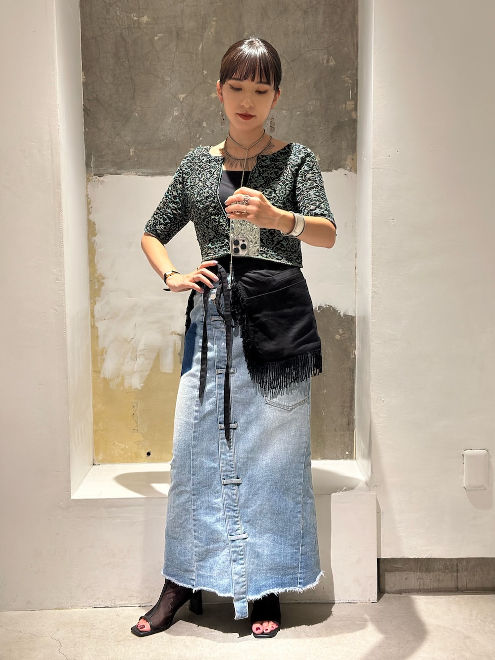 ブルー系のデニムスカート、ブラック系のブーツ、ブラック系のスカートを着用したレディースの秋コーディネートの2枚目の写真