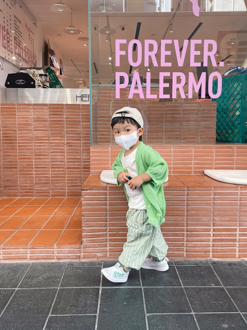 グリーン系のノーカラーコートを着用したレディースの秋コーディネートの2枚目の写真