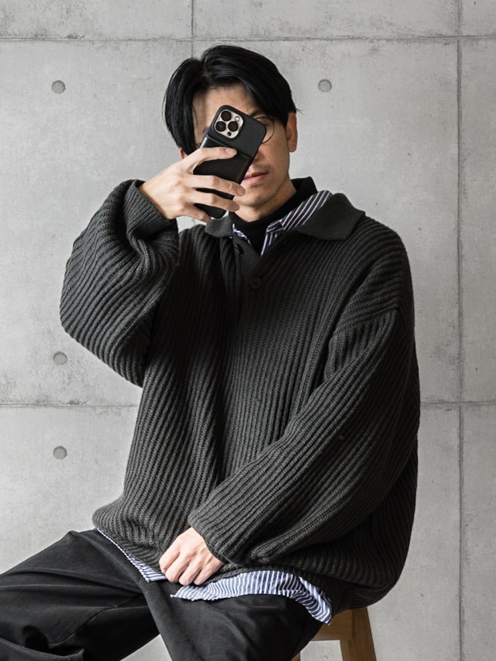 ブラック系のニット/セーター、ブルー系のシャツ/ブラウス、ホワイト系のスニーカーを着用したメンズの秋コーディネートの2枚目の写真