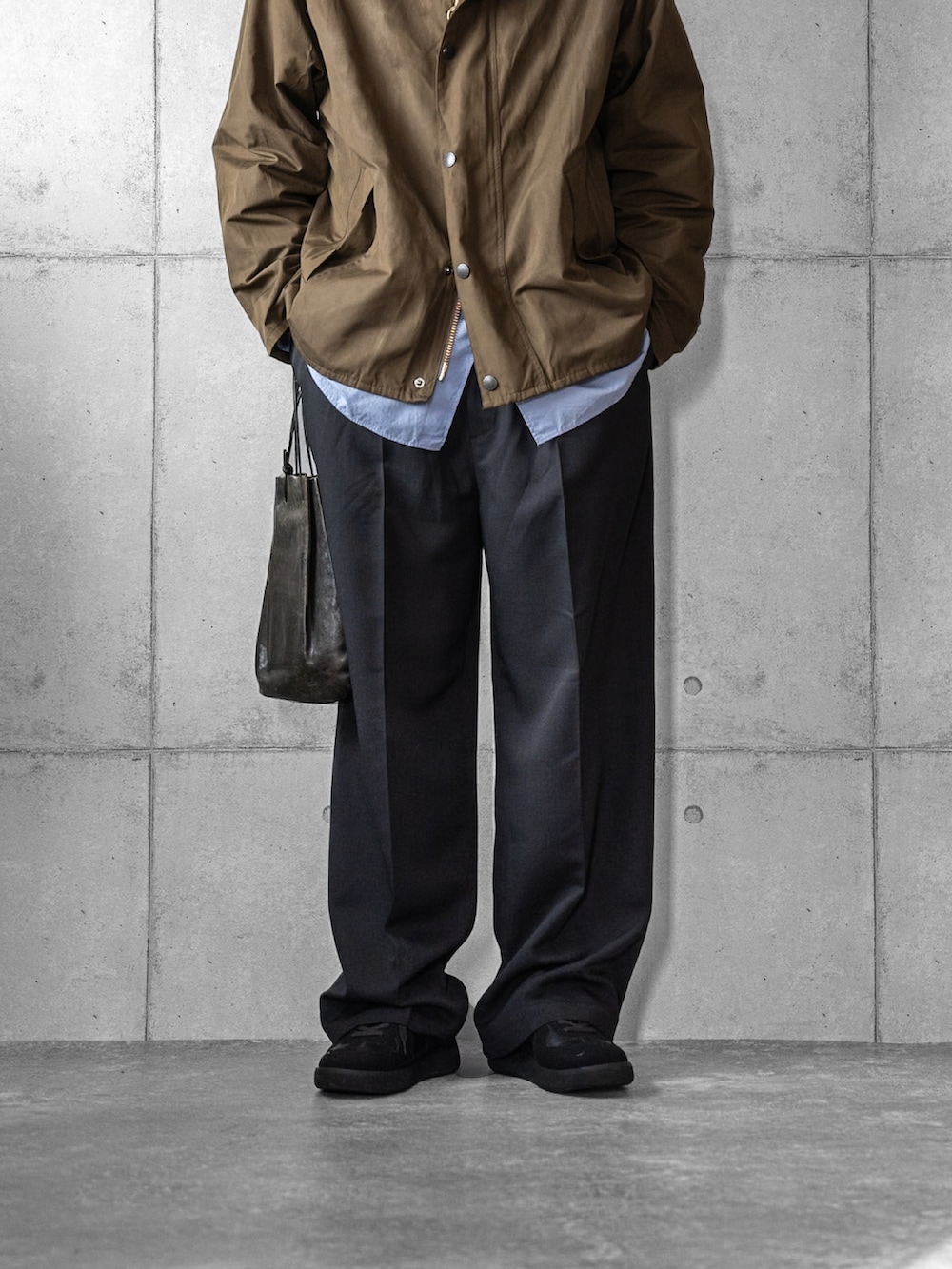 ブラック系のスラックス、ブラック系のショルダーバッグ、ブラック系のスニーカーを着用したメンズの冬コーディネートの3枚目の写真