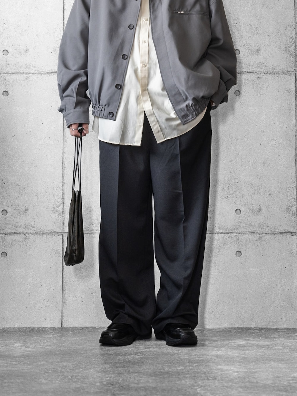 グレー系のブルゾン、イエロー系のシャツ/ブラウス、ブラック系のスラックスを着用したメンズの春コーディネートの3枚目の写真