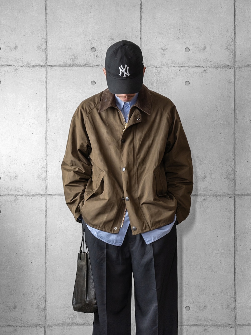 ブラック系のスラックス、ブラック系のショルダーバッグ、ブラック系のスニーカーを着用したメンズの冬コーディネートの2枚目の写真