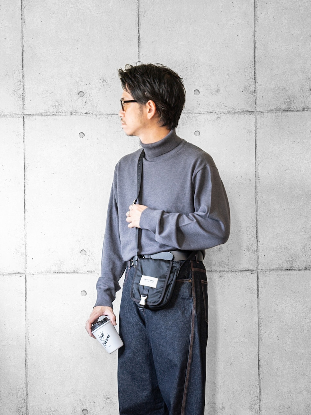 グレー系のニット/セーター、ブルー系のデニムパンツ、ホワイト系のスニーカーを着用したメンズの秋コーディネートの2枚目の写真