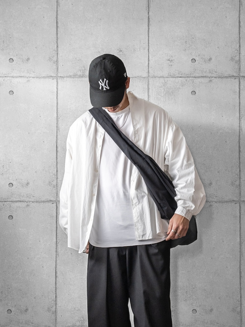 グリーン系のスニーカー、ブラック系のスラックス、ブラック系のショルダーバッグを着用したメンズの春コーディネートの2枚目の写真