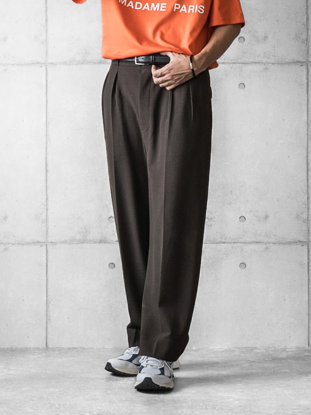 オレンジ系のTシャツ/カットソー、ブラウン系のスラックス、ホワイト系のスニーカーを着用したメンズの夏コーディネートの5枚目の写真