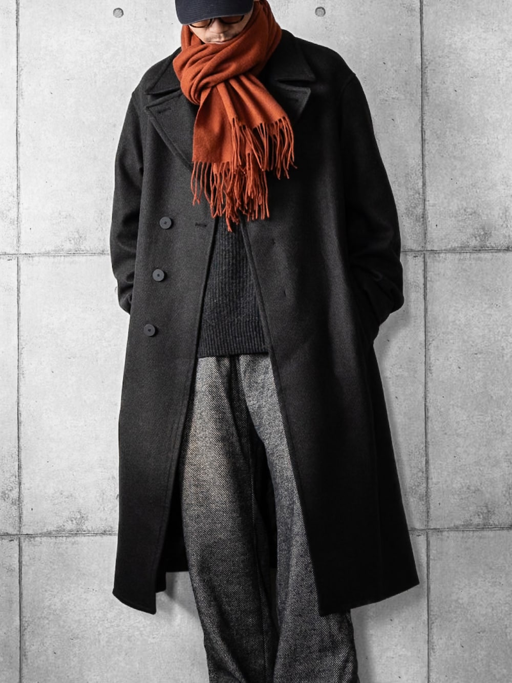 グレー系のチェスターコート、グレー系のニット/セーター、グレー系のスラックスを着用したメンズの冬コーディネートの2枚目の写真