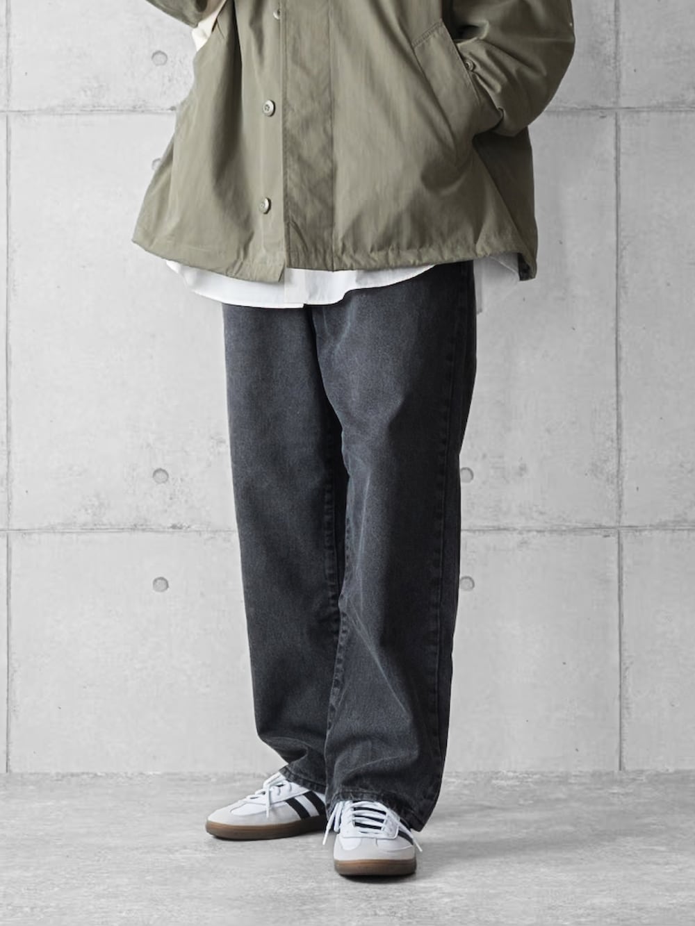 グリーン系のブルゾン、ブラック系のデニムパンツ、ホワイト系のスニーカーを着用したメンズの春コーディネートの4枚目の写真