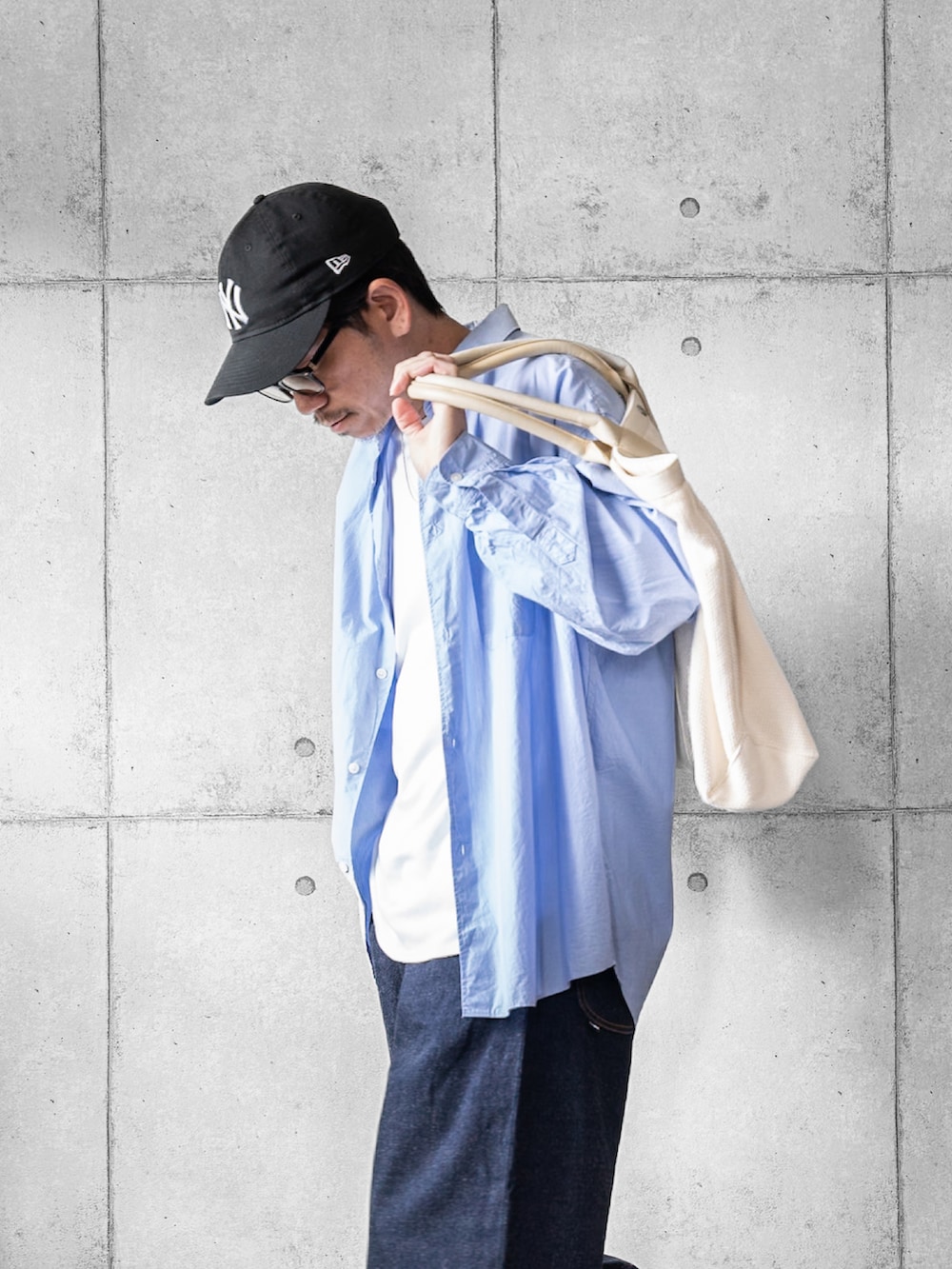 ブルー系のデニムパンツ、ブルー系のシャツ/ブラウス、ベージュ系のトートバッグを着用したメンズの春コーディネートの2枚目の写真