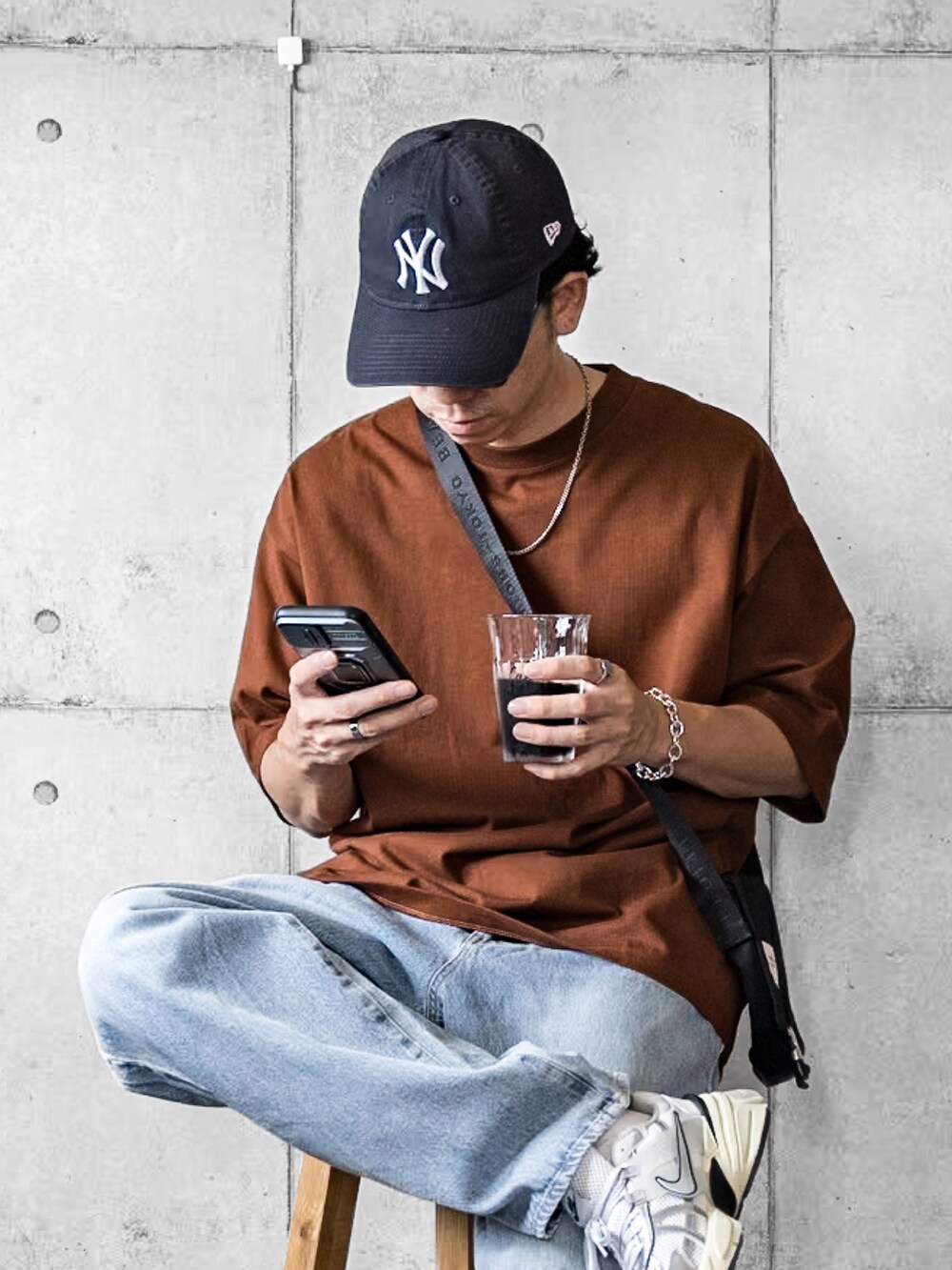 ブラウン系のTシャツ/カットソー、ブルー系のデニムパンツ、ホワイト系のスニーカーを着用したメンズの夏コーディネートの2枚目の写真