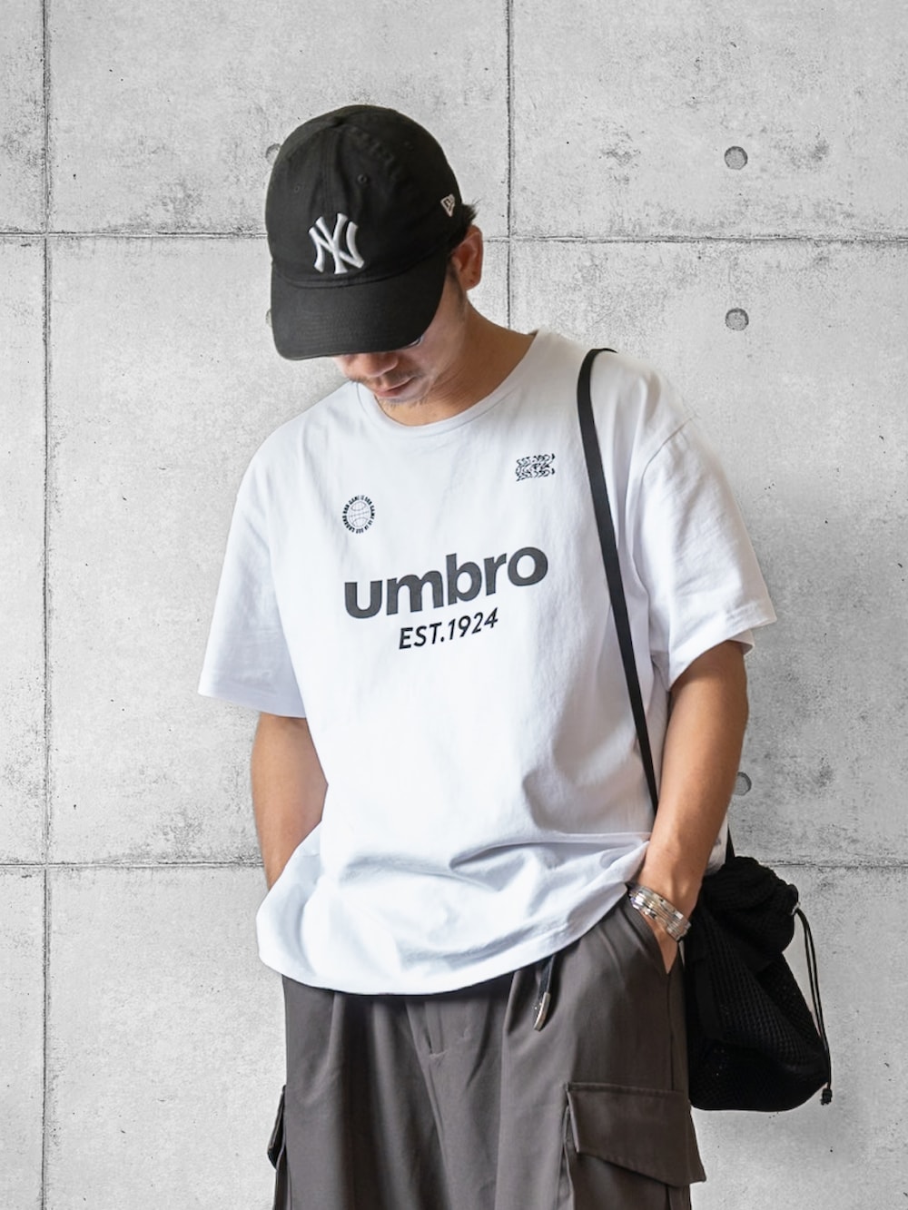 ホワイト系のTシャツ/カットソー、グレー系のその他パンツ、ブラック系のショルダーバッグを着用したメンズの夏コーディネートの2枚目の写真