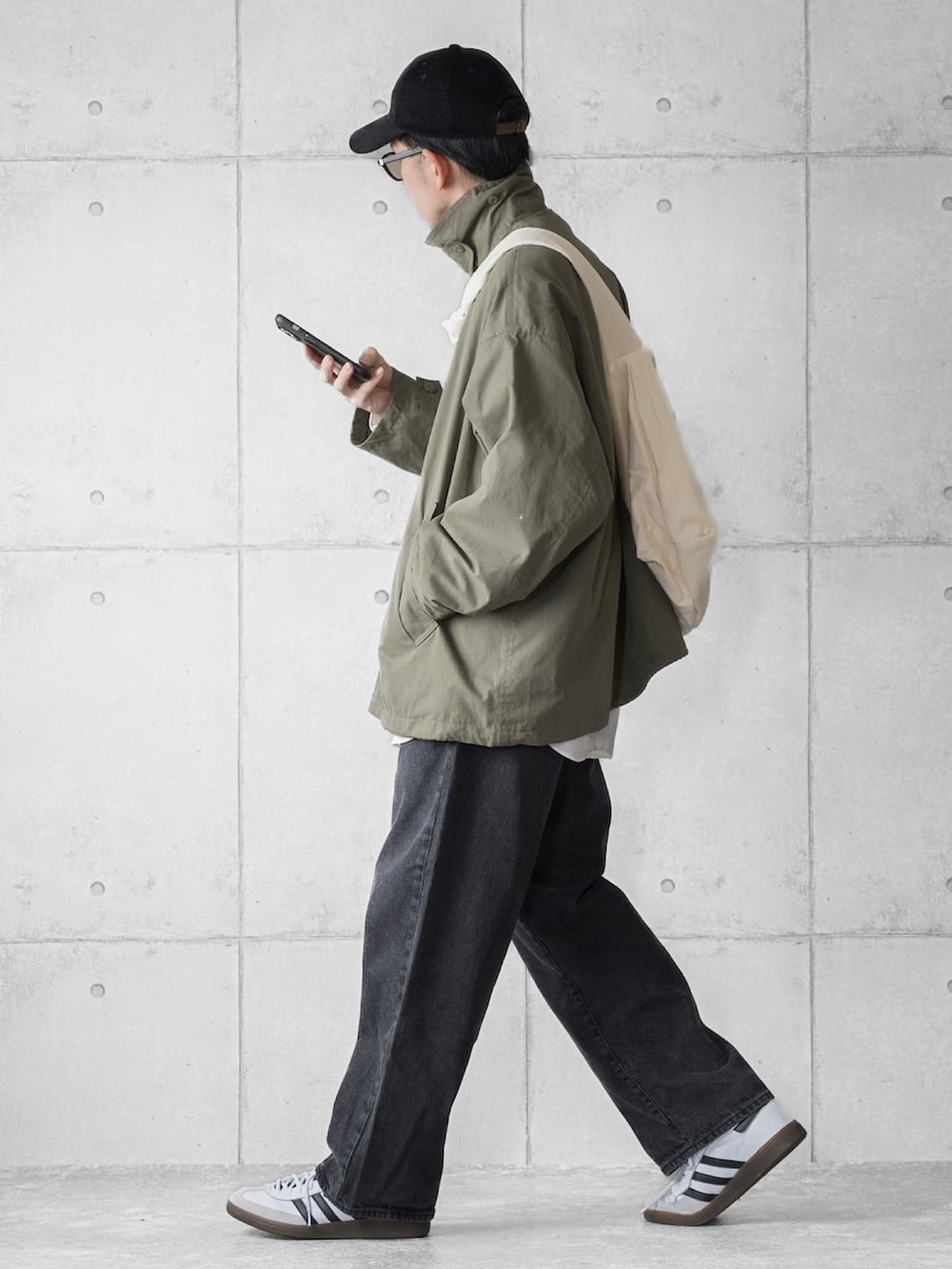 グリーン系のブルゾン、ブラック系のデニムパンツ、ホワイト系のスニーカーを着用したメンズの春コーディネートの2枚目の写真