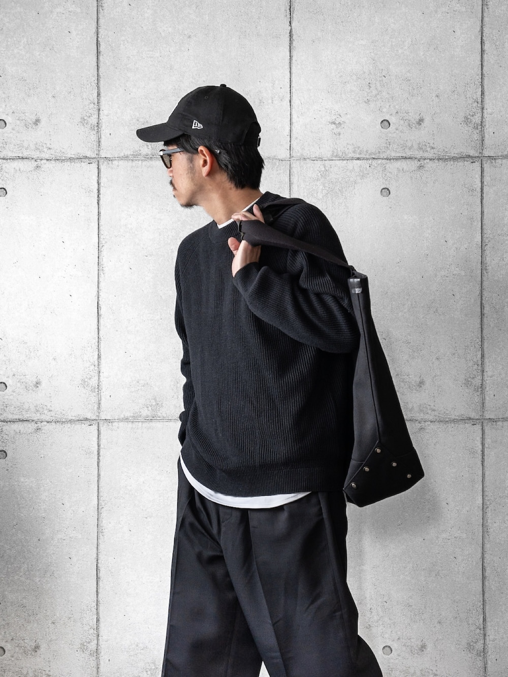 グレー系のニット/セーター、ブラック系のスラックス、ブラック系のトートバッグを着用したメンズの冬コーディネートの2枚目の写真