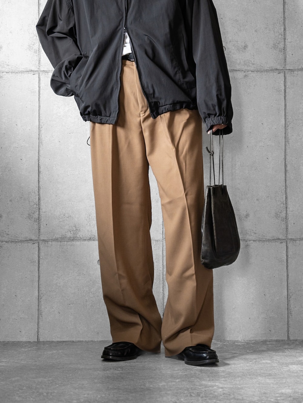 ブラック系のジャージ、ベージュ系のスラックス、ブラック系のショルダーバッグを着用したメンズの秋コーディネートの3枚目の写真