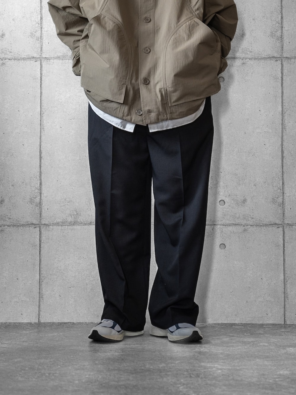 グリーン系のポンチョ、ブラック系のスラックス、ホワイト系のシャツ/ブラウスを着用したメンズの春コーディネートの3枚目の写真