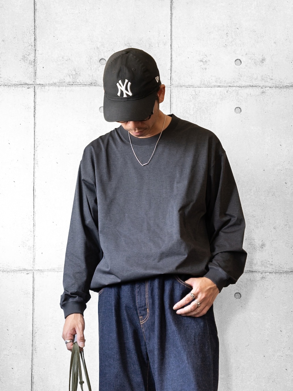 グリーン系のショルダーバッグ、ブラック系のスニーカー、グレー系のTシャツ/カットソーを着用したメンズの夏コーディネートの2枚目の写真