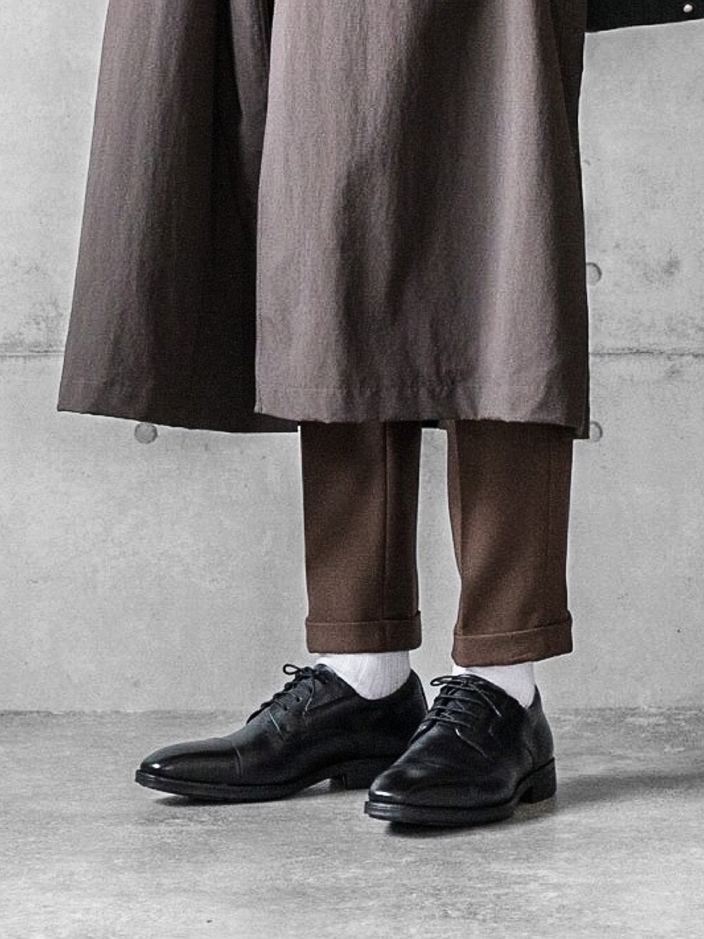 ブラック系のドレスシューズ、ブラック系のトートバッグ、ブラウン系のステンカラーコートを着用したメンズの秋コーディネートの5枚目の写真