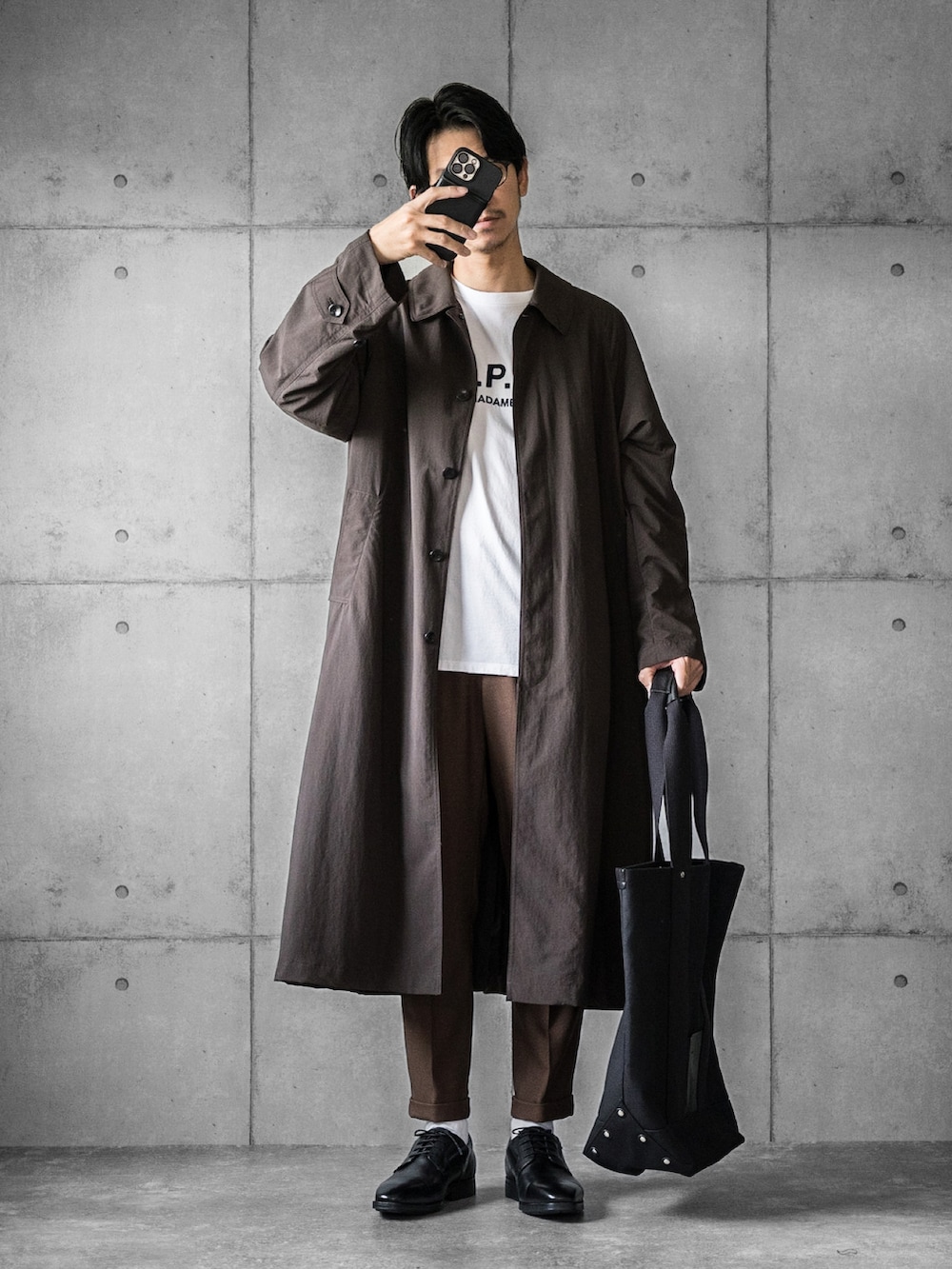 ブラック系のドレスシューズ、ブラック系のトートバッグ、ブラウン系のステンカラーコートを着用したメンズの秋コーディネートの3枚目の写真