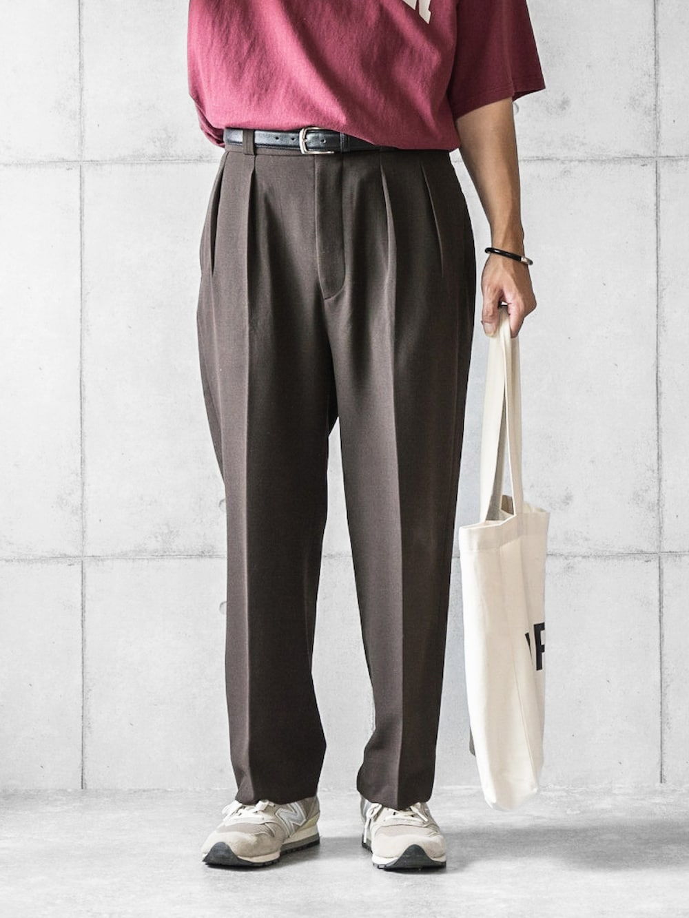 レッド系のTシャツ/カットソー、ブラウン系のスラックス、ホワイト系のトートバッグを着用したメンズの夏コーディネートの4枚目の写真