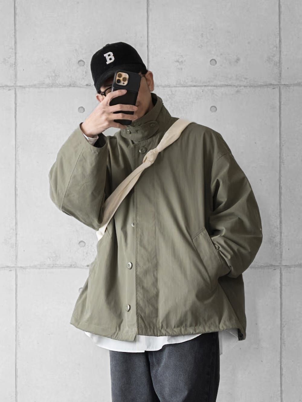 グリーン系のブルゾン、ブラック系のデニムパンツ、ホワイト系のスニーカーを着用したメンズの春コーディネートの3枚目の写真