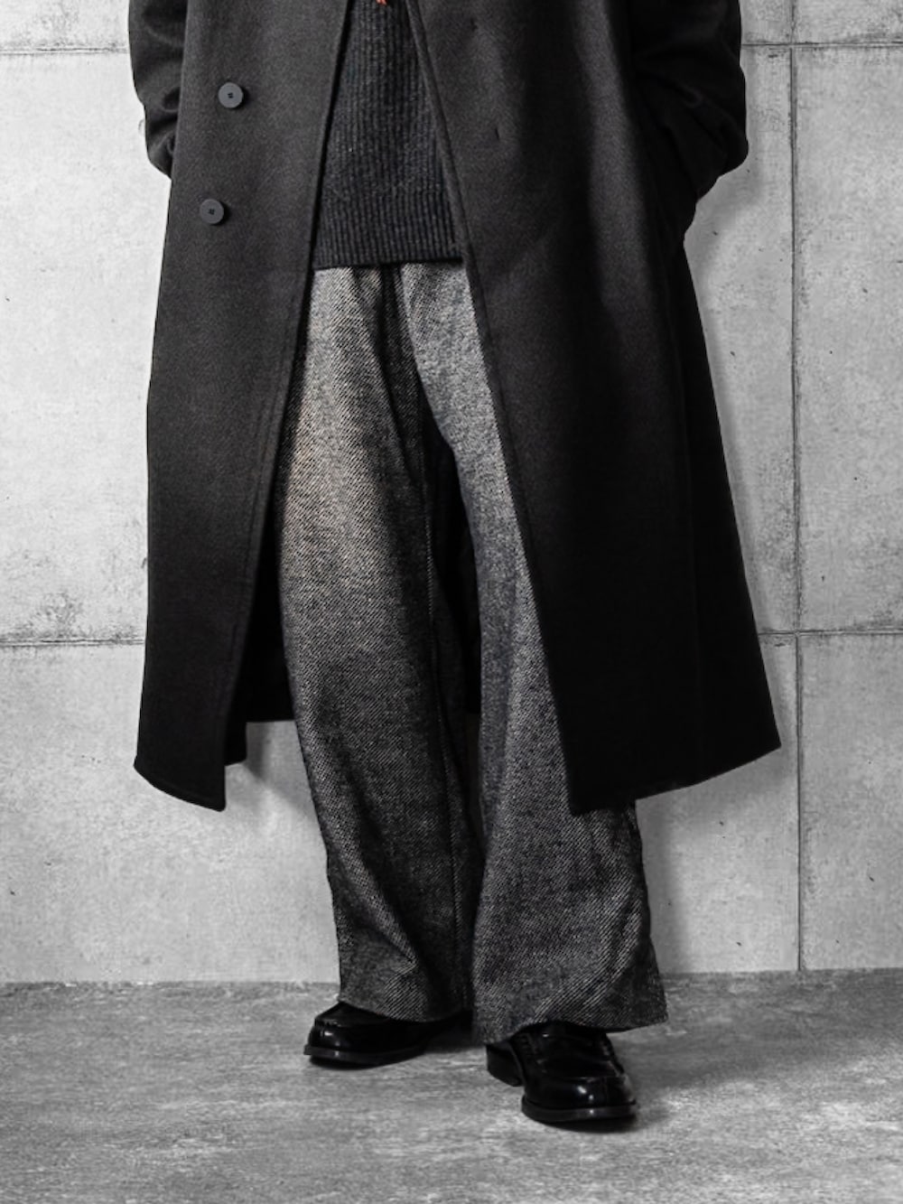 グレー系のチェスターコート、グレー系のニット/セーター、グレー系のスラックスを着用したメンズの冬コーディネートの3枚目の写真