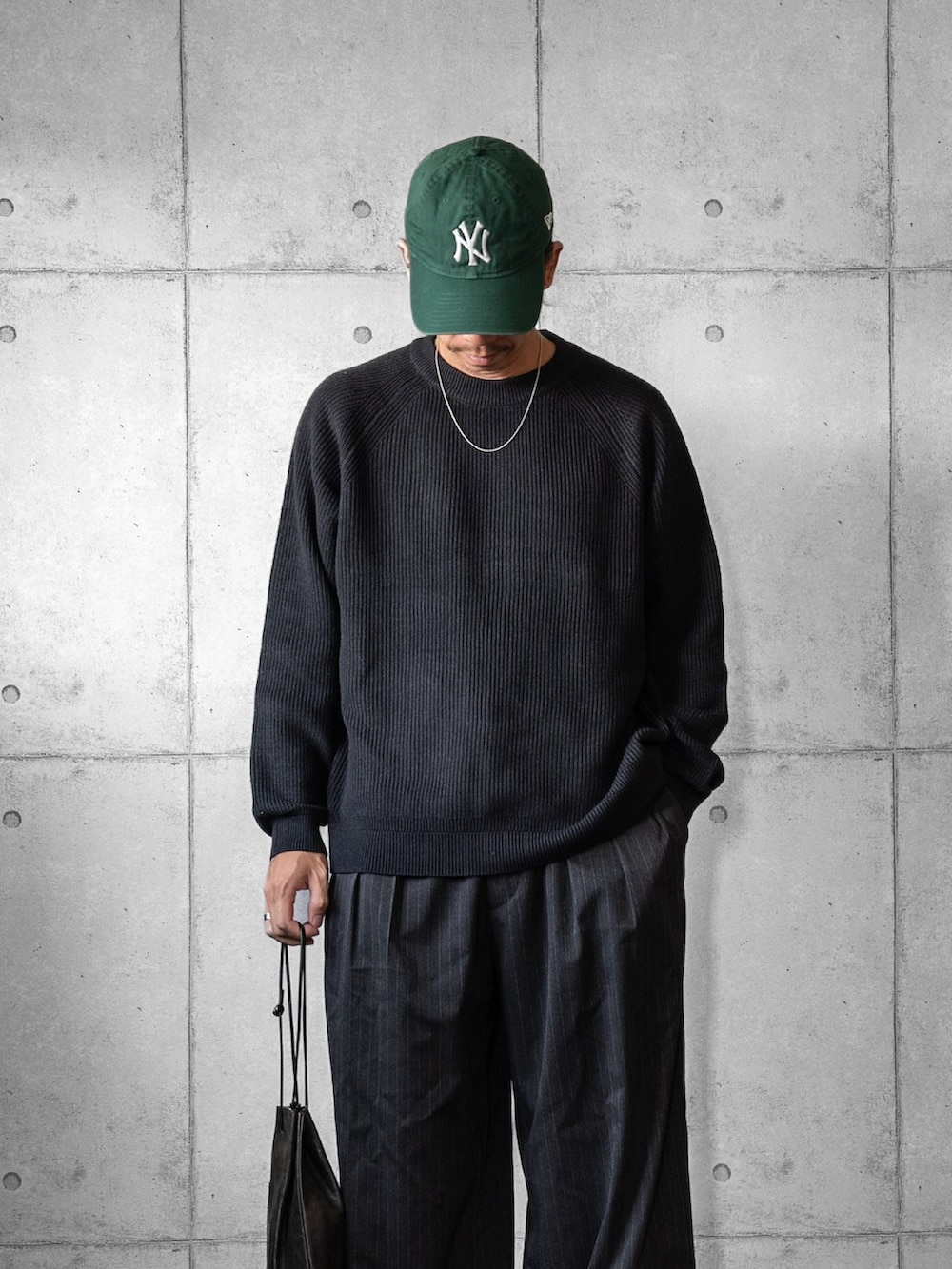 ブラック系のショルダーバッグ、グレー系のニット/セーター、グレー系のスラックスを着用したメンズの秋コーディネートの2枚目の写真