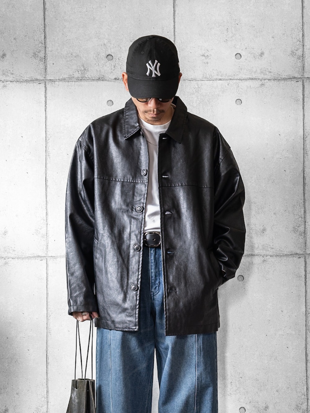 ブラック系のブルゾン、ブルー系のデニムパンツ、ブラック系のショルダーバッグを着用したメンズの春コーディネートの2枚目の写真