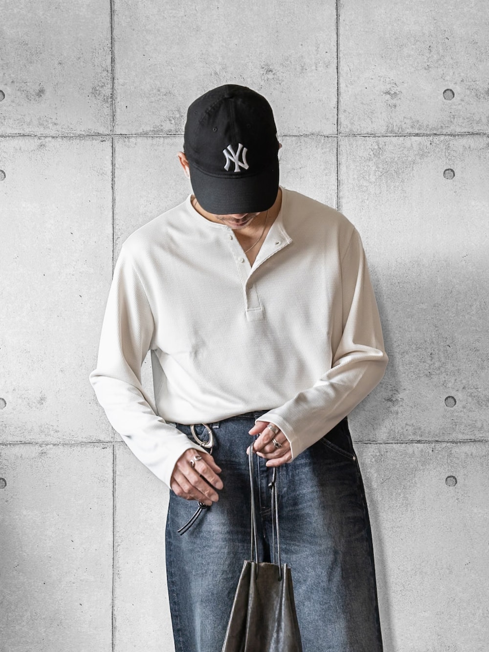 ブラック系のショルダーバッグ、ホワイト系のTシャツ/カットソー、ブルー系のデニムパンツを着用したメンズの春コーディネートの2枚目の写真