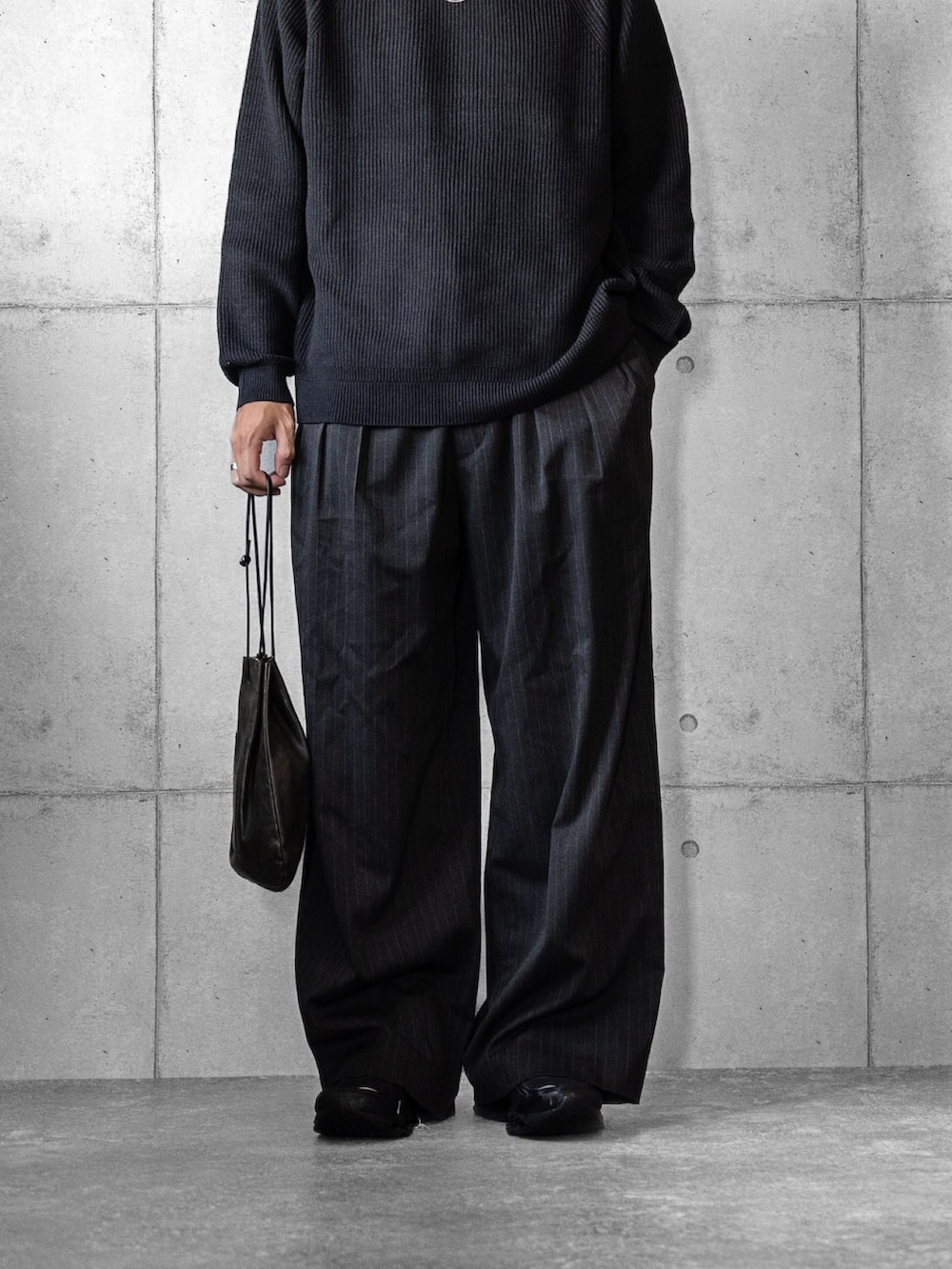 ブラック系のショルダーバッグ、グレー系のニット/セーター、グレー系のスラックスを着用したメンズの秋コーディネートの3枚目の写真