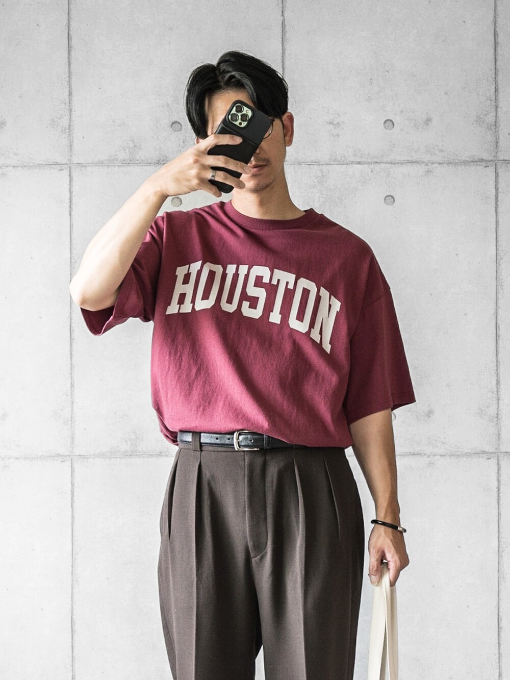レッド系のTシャツ/カットソー、ブラウン系のスラックス、ホワイト系のトートバッグを着用したメンズの夏コーディネートの3枚目の写真