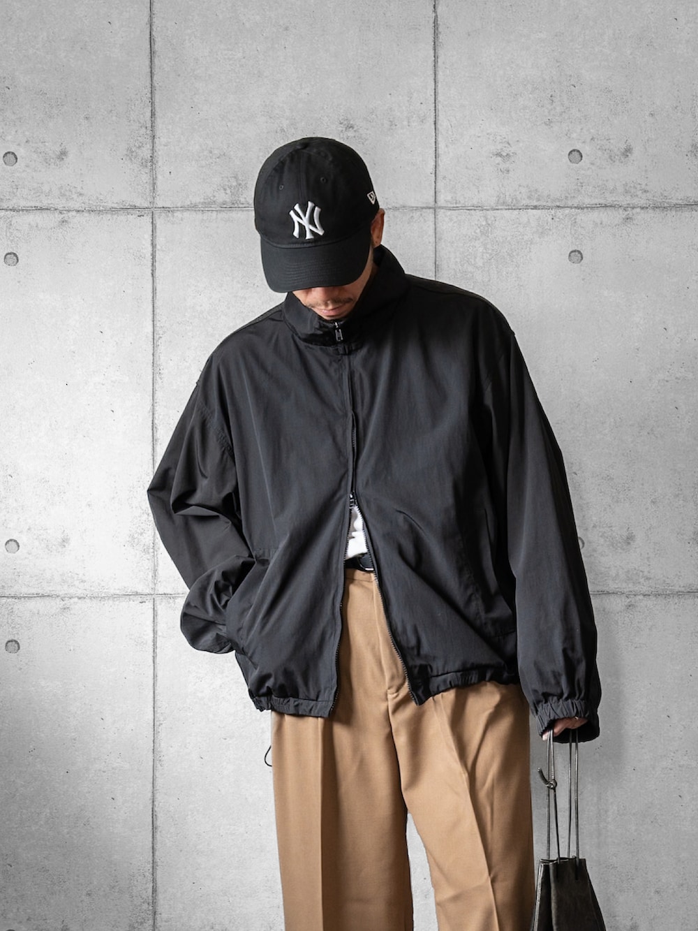 ブラック系のジャージ、ベージュ系のスラックス、ブラック系のショルダーバッグを着用したメンズの秋コーディネートの2枚目の写真