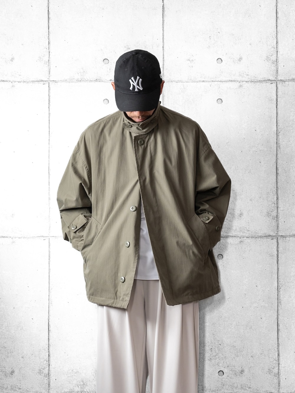 ホワイト系のスラックス、ブラック系のスニーカー、グリーン系のブルゾンを着用したメンズの春コーディネートの3枚目の写真