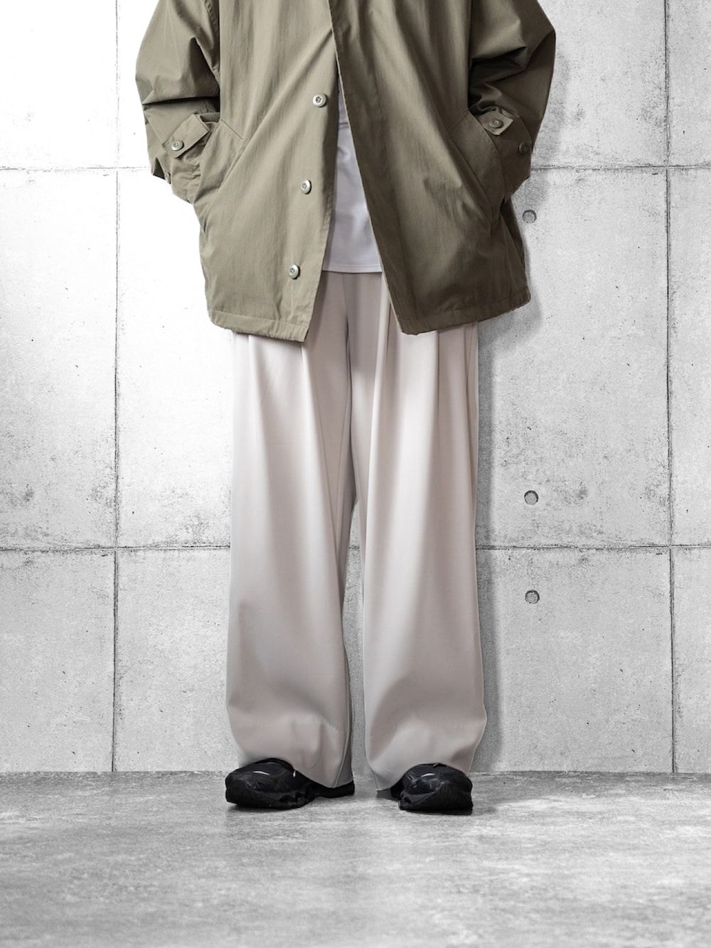 ホワイト系のスラックス、ブラック系のスニーカー、グリーン系のブルゾンを着用したメンズの春コーディネートの4枚目の写真