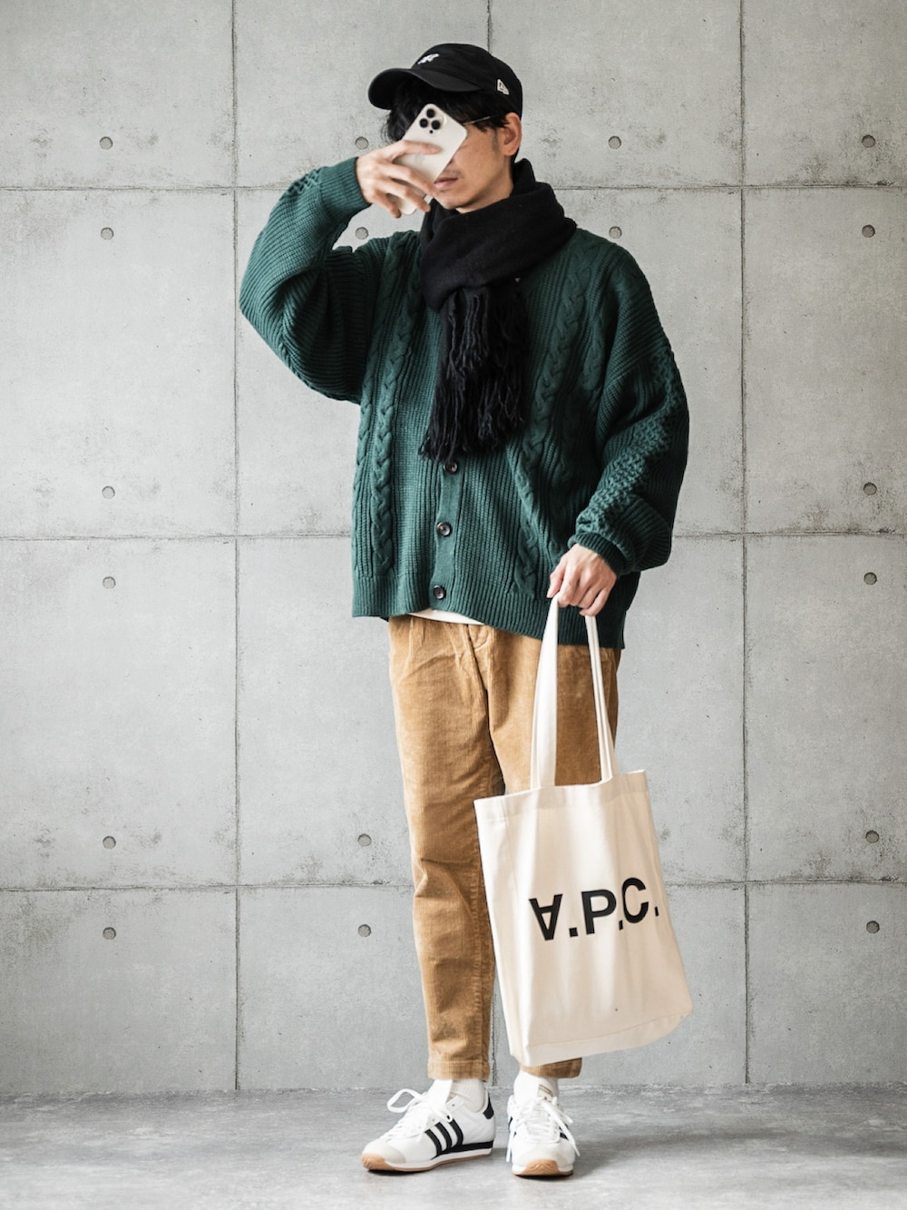 グリーン系のカーディガン/ボレロ、ベージュ系のスラックス、ホワイト系のスニーカーを着用したメンズの秋コーディネートの2枚目の写真