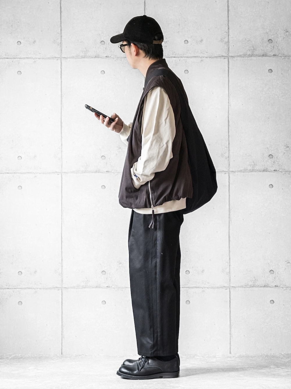 ブラウン系のブルゾン、ブラック系のパンツ、ブラック系のブーツを着用したメンズの春コーディネートの2枚目の写真